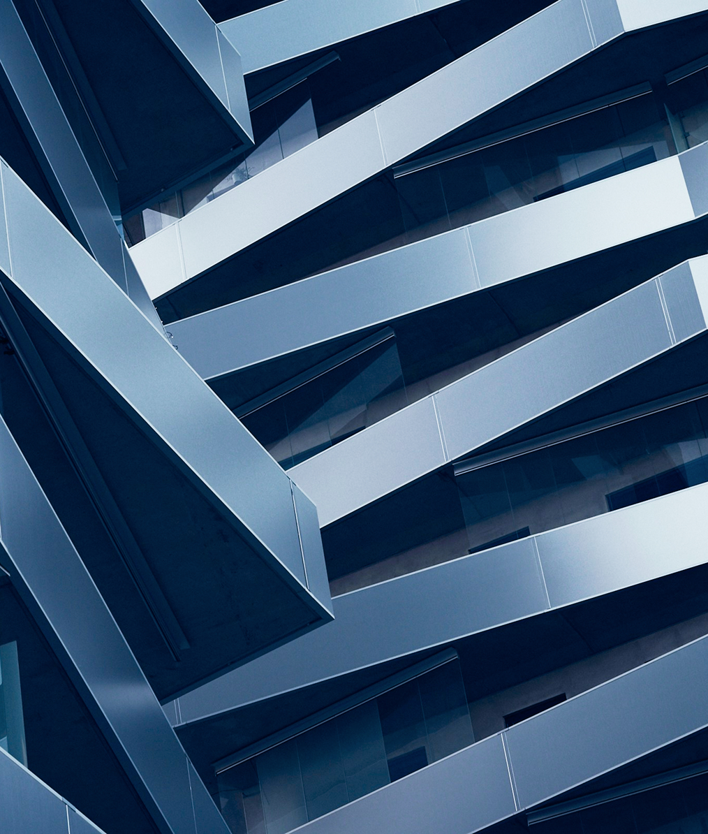 Abstract close-up of modern building facade with overlapping metallic beams and glass panels in blue tones.
